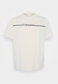 Valge puuvillane T-särk lühikeste varrukatega, millel on must horisontaalne joone ja rinnal script-tähega trükitud "Calvin Klein".