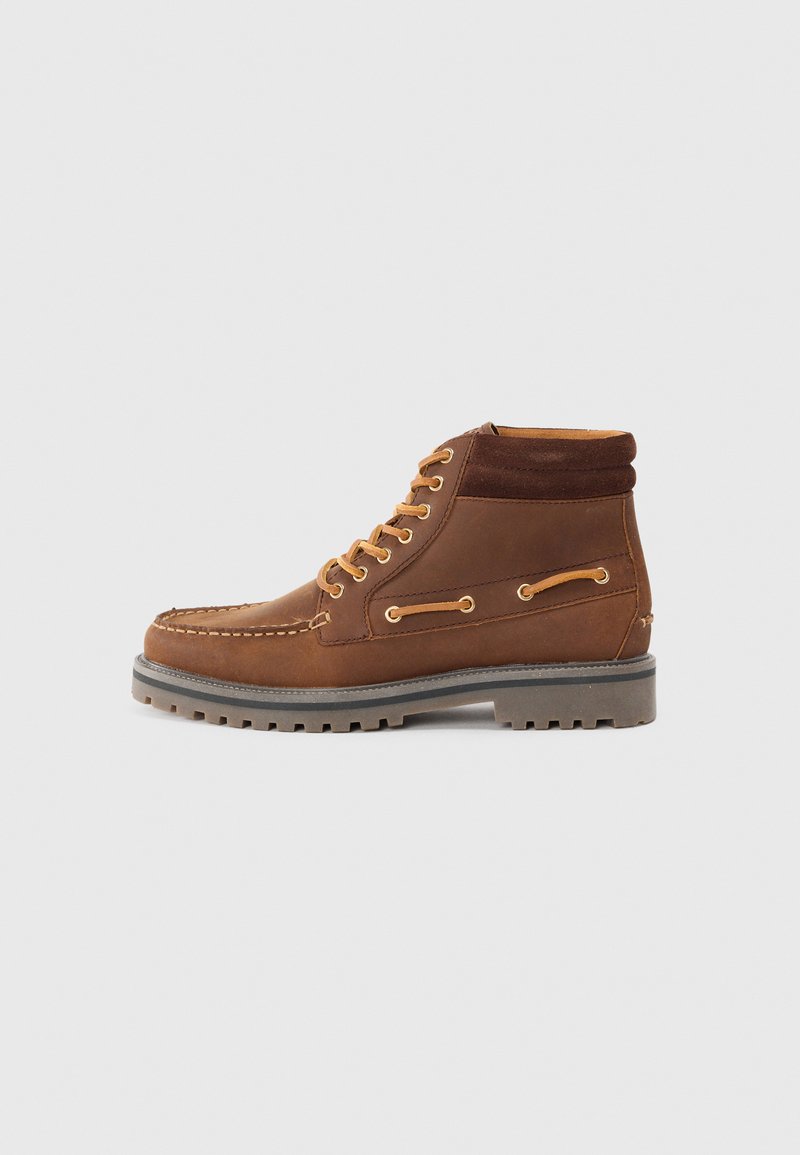 Brown leather ankle boots with suede collar, contrasting laces, and a cleated rubber sole. Features decorative stitching and side accents.