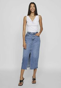 Denim skirt with front slit, mid-calf length, light blue wash. Paired with a white sleeveless top and black strappy heels. Smooth texture.