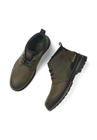 Bottines en cuir marron avec une finition texturée, semelles en caoutchouc noir et design à lacets. Comprend une languette et un détail de logo.