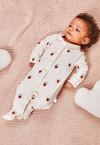 Body neonato bianco con motivo di fragole rosse, dotato di colletto arrotondato e chiusure a scatto, posato su una coperta rosa strutturata.