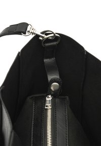 Black leather bag interior with smooth texture, features a zipper pocket and a metallic snap button, showcasing a minimalist design.