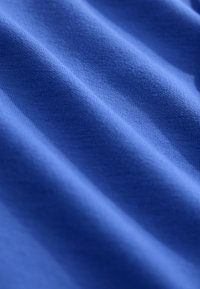 Kék szövet puha tapintással, finom hullámokkal és sima, egyenletes szövésmintával. Látható minták vagy szerelési részletek nélkül.