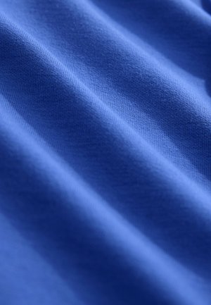 Modra tkanina z mehko teksturo, ki prikazuje subtilne valove in gladko, enakomerno tkanino. Brez vidnih vzorcev ali kovinske opreme.
