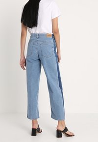 Světle modré džíny s rovnými nohavicemi, se zvýrazněným panelem, pěti kapsami a značkovou nášivkou na zadním pásu.