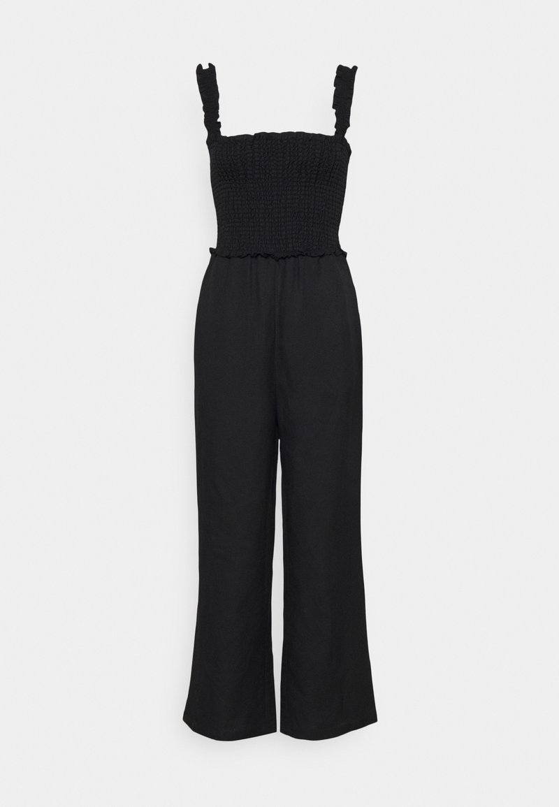 Combinaison noire sans manches avec corsage ajusté froncé, bretelles volantées et pantalons larges sur fond blanc uni.