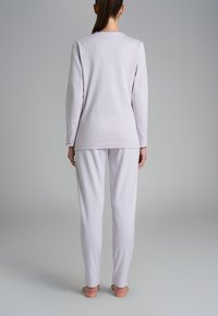 Top viola chiaro a maniche lunghe con scollatura tonda abbinato a pantaloni bianchi con un sottile motivo a pois. Tessuto morbido e liscio.