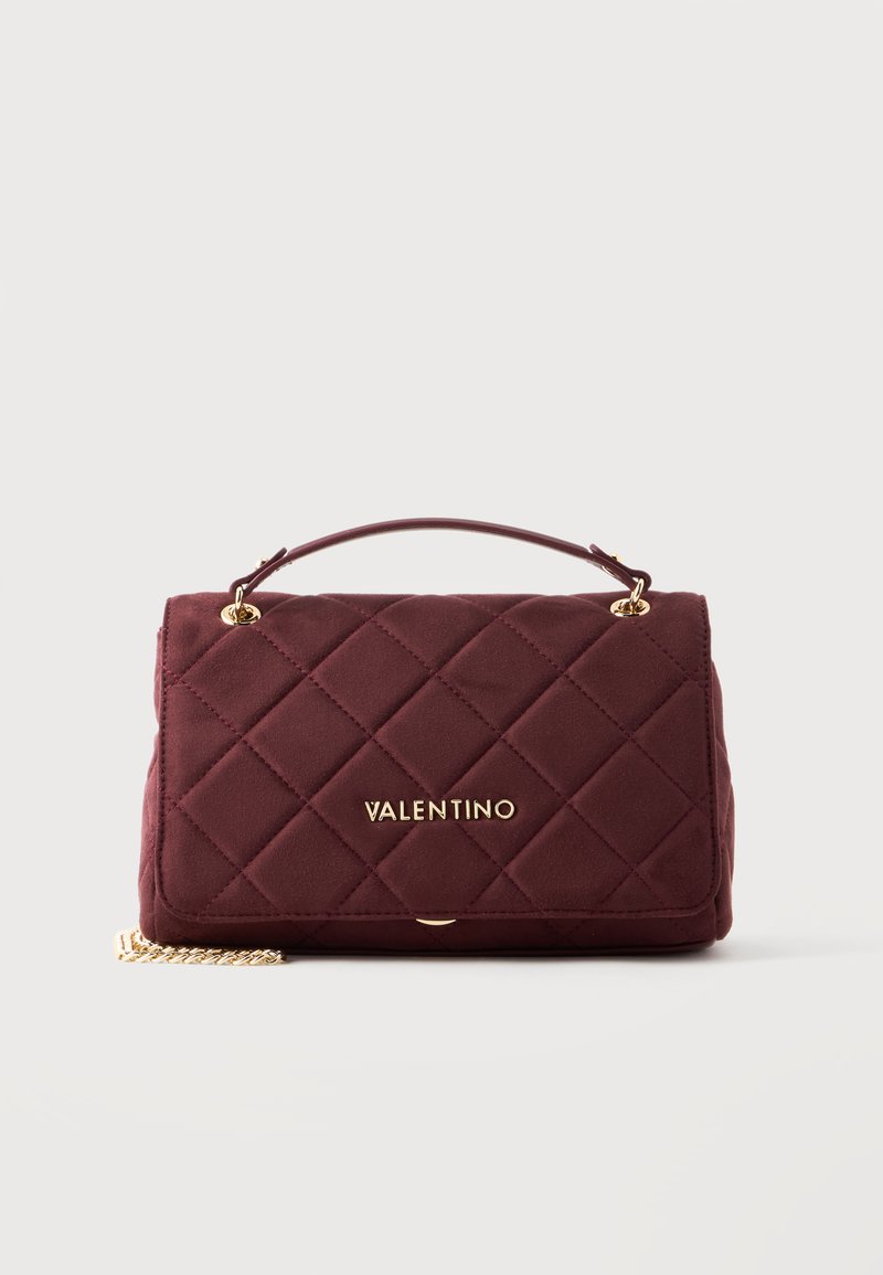 Бордо капитонирана чанта с златна верижка, горна дръжка и златно лого на Valentino отпред, поставена на едноцветен фон.