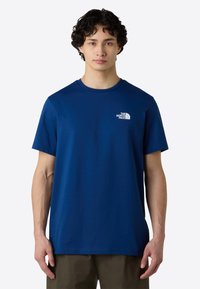 Námořnickomodré bavlněné tričko s krátkými rukávy, kulatým výstřihem a malým bílým logem na levé části hrudi. Hladká textura a uvolněný střih.