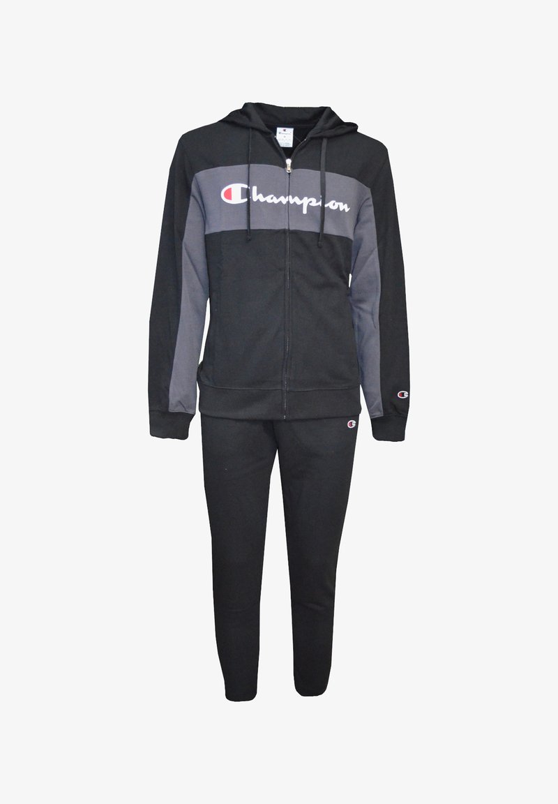 Svart Champion träningsdräkt, bestående av en zip-up hoodie med grå detaljer och matchande byxor. Mjuk tyg med logotypdetalj på framsidan och benet.