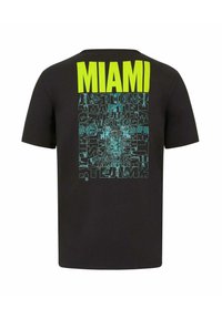 Czarna koszulka z krótkim rękawem z dużym, wyraźnym napisem "MIAMI" w neonowej zieleni z tyłu, z misternymi niebieskimi wzorami tekstowymi związanymi z "Aston Martin".