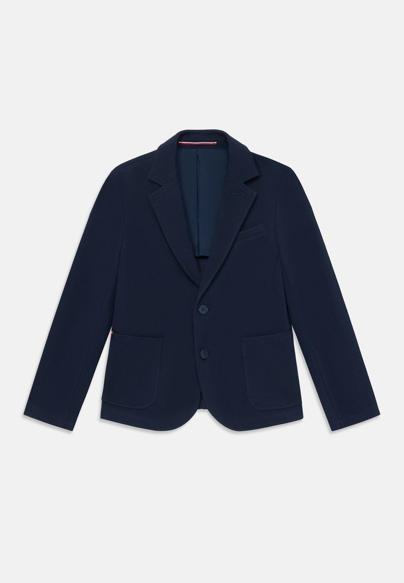 Námořnické modré sako vyrobené z texturované tkaniny, které má klopové límce, dvě přední kapsy a zapínání na dva knoflíky. Vnitřek je podšitý kontrastní barvou.