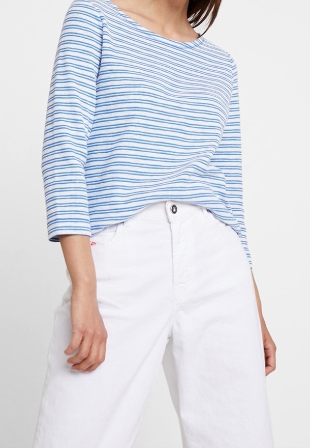 Haut à manches longues rayé bleu et blanc avec un large col, associé à un pantalon blanc taille haute. Tissu en mélange de coton, coupe décontractée.