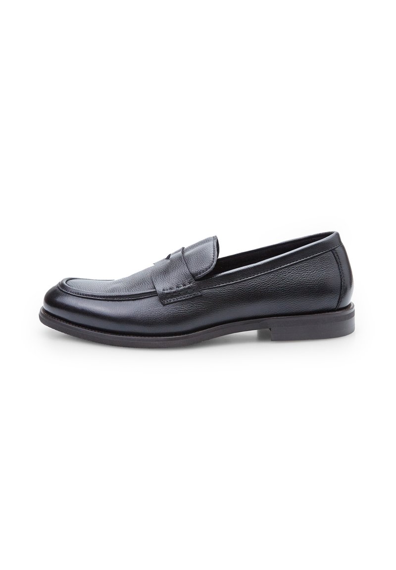 Mocasines de piel negra con un acabado suave, puntera redondeada y tacón bajo. Presenta una correa decorativa y detalles de costura en la parte frontal.