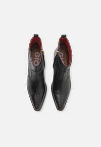 Botas negras de tobillo hechas de cuero texturizado con punta afilada, con una cremallera dorada y forro rojo. Destacan por su diseño elegante.