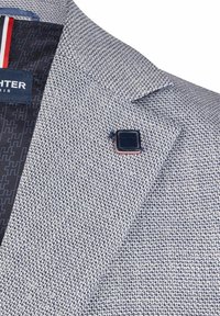 Blazer aus strukturiertem, hellgrauem Stoff mit marinefarbenen Akzenten, bietet einen Reverskragen, eine kleine Reversnadel und ein gemustertes Innenfutter.