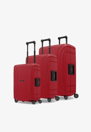 Tre valigie rigide rosse di dimensioni diverse con superfici testurizzate, ruote nere e manici retrattili; dotate di lucchetti a combinazione.