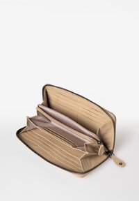 Portafogli in pelle beige con chiusura a zip, numerosi scomparti per carte e due compartimenti foderati in tessuto chiaro con una superficie liscia.