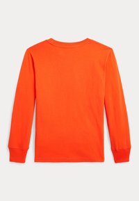 Langarm-T-Shirt aus leuchtend orangefarbenem Baumwollstoff. Mit Rundhalsausschnitt und lockerer Passform, geradem Saum und umgeschlagenen Ärmeln.