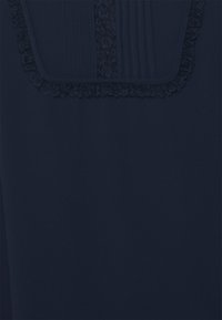 Námorně modrá látka s texturovaným panelem s plisováním a krajkovým lemem. Design zahrnuje dekorativní krajkový akcent podél výstřihu.