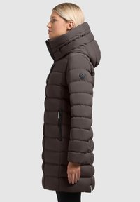Brązowa kurtka puchowa z wysokim kołnierzem, dopasowanym krojem, poziomym pikowaniem, czarnym zamkiem błyskawicznym oraz naszywką z logo na lewym rękawie.