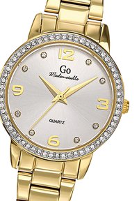 Montre en quartz dorée avec un cadran argenté, ornée de cristaux autour de la lunette, de grands index horaires et d'un bracelet à maillons.