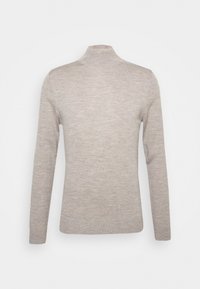 Pull en maille torsadée couleur beige clair avec col roulé, manches longues et bords côtelés sur fond blanc uni.