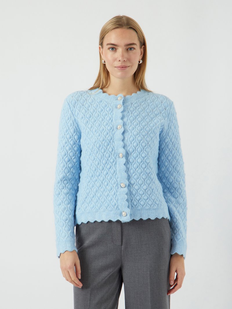 Gilet tricoté bleu clair avec un motif en losange texturé, des bords festonnés et cinq grands boutons en forme de perle sur le devant.