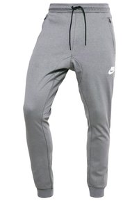 Grå Nike joggerbyxor med svart dragsko, fickor med dragkedja på sidorna och ribbade ankle cuffs.