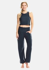 Top cropped de color navy combinado con pantalones sueltos de pierna ancha, ambos fabricados en un tejido suave. Los pantalones cuentan con bolsillos frontales y una cintura elástica.