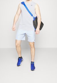 Gray sleeveless athletic shirt, light blue shorts, black shoulder bag with blue accents, and blue athletic shoes with black soles and details.