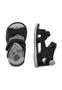 Sandales en cuir noir avec des sangles ajustables, un design découpé, des semelles en caoutchouc grises, et marquées de la taille 18 et "vera pelle" sur la semelle intérieure.