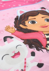 Tissu rose avec une illustration d'une fille aux cheveux bouclés portant une veste rose, faisant signe de la main à côté d'un personnage de chat blanc souriant.