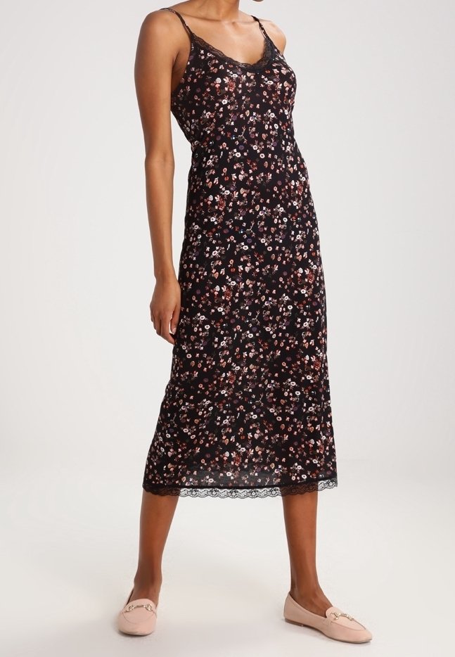 Schwarzes Blumenkleid mit dünnen Trägern, Spitzenbesatz und einem knielangen Saum. Es hat ein kleines Blumenmuster in Rosa- und Weißtönen.