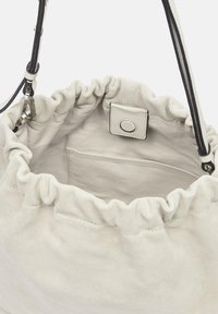 Jasnoszara torba typu bucket z marszczonym otworem, gładką teksturą, wewnętrzną kieszenią i regulowanym, płaskim paskiem na ramię. Zamyka się na zatrzask.