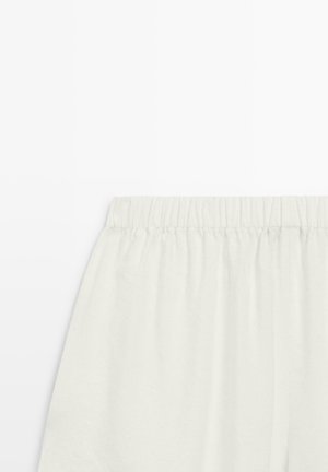 Hvid nederdel med elastisk talje, blødt tekstureret stof, plisseret design, vist mod en ensfarvet hvid baggrund.