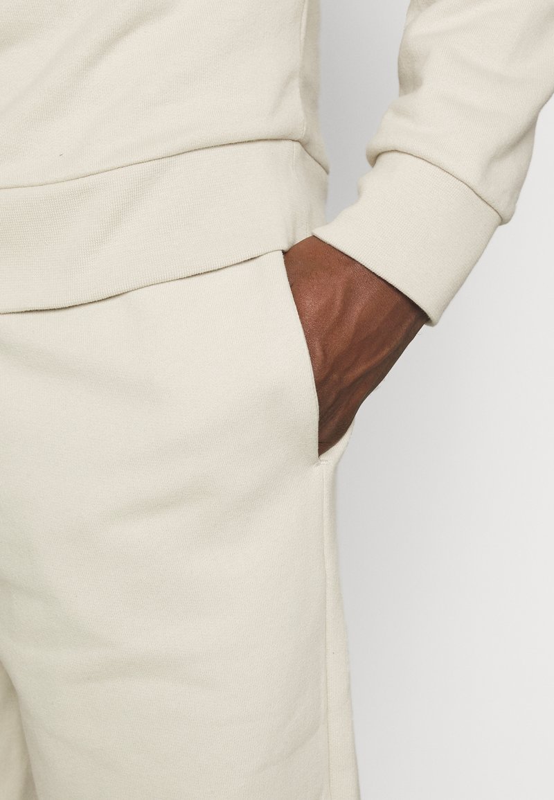 Herren Trainingsanzüge | pinqponq UNISEX Jogginghose cliff beige/beige - LS51181 Herren Trainingsanzüge | pinqponq UNISEX Jogginghose cliff beige/beige - LS51181