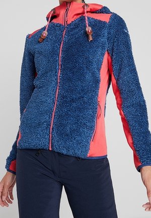 Blau-rote Fleecejacke mit Reißverschluss, strukturierter Vorderseite, roten Seitenpaneelen, Kapuze mit verstellbaren Kordeln, getragen zu dunkler Hose.