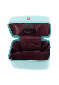 Maleta dura de color turquesa claro con apertura con cremallera, que presenta un interior burdeos, compartimentos y un espacio para el asa.