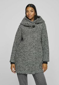 Gray and black patterned coat with a large hood and a button closure. Features loose-fit sleeves with ribbed cuffs and a textured fabric.