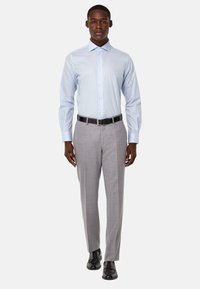 Camisa de vestir a rayas en azul claro con cuello de punta, combinada con pantalones de vestir grises y zapatos negros, con una textura suave y un ajuste a medida.