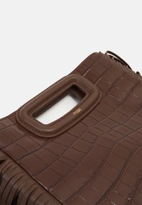 Brun faux læder håndtaske med et tekstureret krokodillemønster, der har et rektangulært håndtag og frynse-detaljer. Guld-branding er synlig.