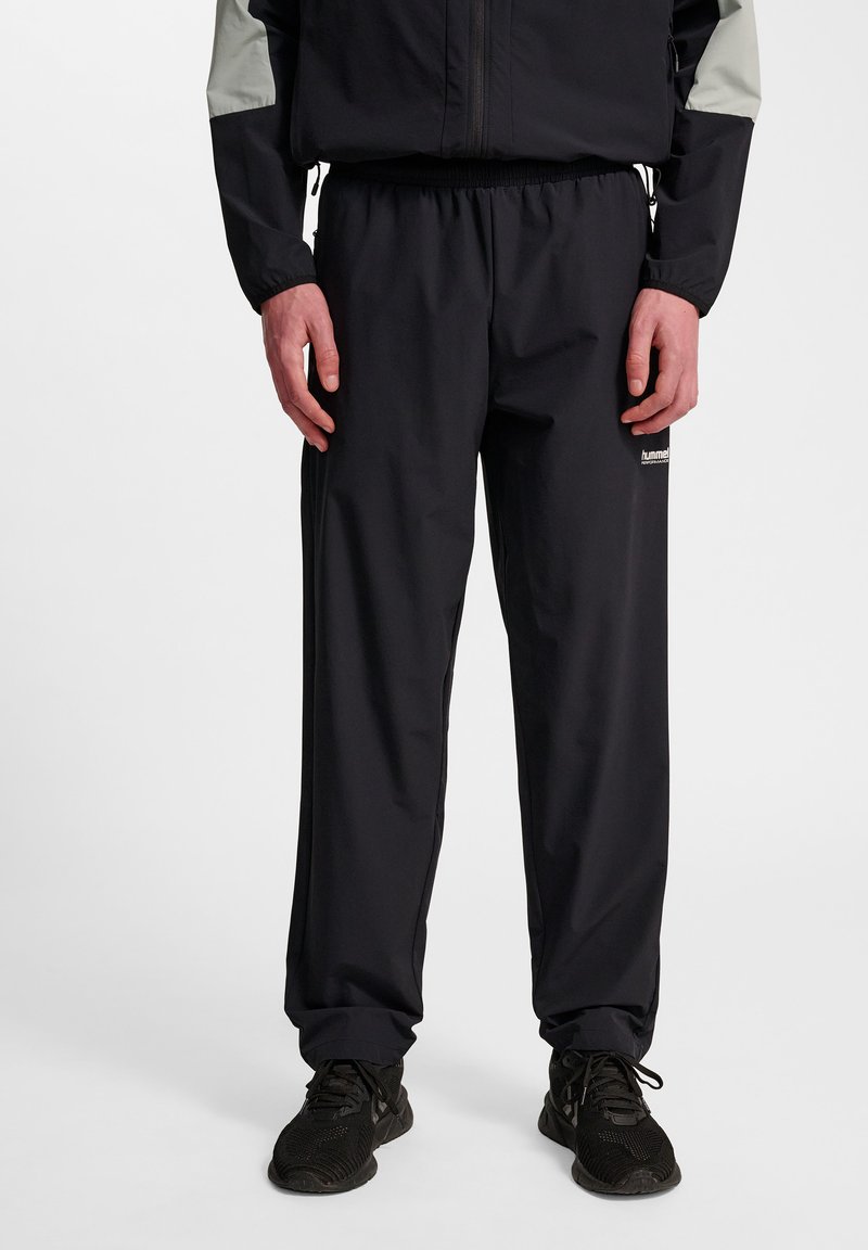 Zwarte sportieve broek van lichtgewicht materiaal, met een elastische tailleband, rechte snit en minimale branding aan de zijkant.