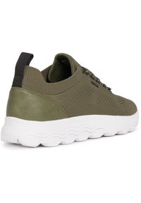 Scarpa sportiva verde oliva con tomaia in maglia, punta rotonda, collo elastico e suola bianca ondulata. Presenta motivi testurizzati e lacci.