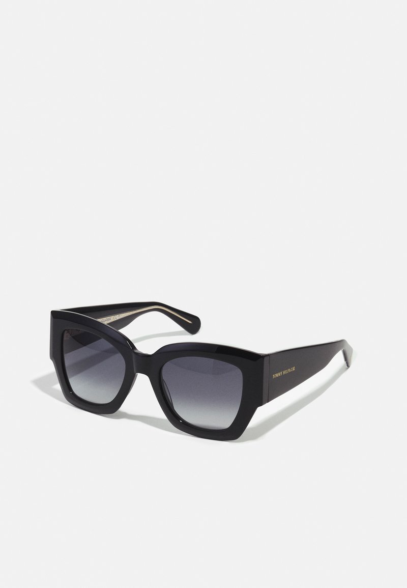 Ochelari de soare supradimensionați, de culoare neagră, cu o ramă geometrică, lentile degradate și o culoare contrastantă pe brațul interior. Logo vizibil pe lateral.