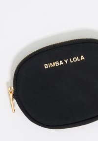 Črna tkaninska kozmetična torbica z zlatim zadrgo in dodatki; "BIMBA Y LOLA" vtisnjeno v zlatem napisu spredaj. Okrogla oblika.