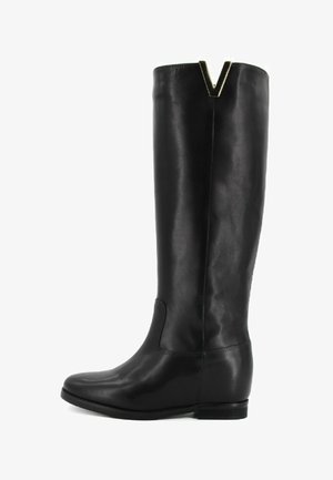 Stivale in pelle nera al ginocchio con tacco piatto, punta arrotondata e un accento metallico a forma di V nella parte superiore. Texture liscia e design semplice.