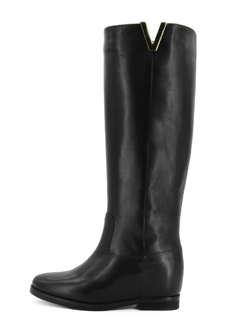Stivale in pelle nera al ginocchio con tacco piatto, punta arrotondata e un accento metallico a forma di V nella parte superiore. Texture liscia e design semplice.