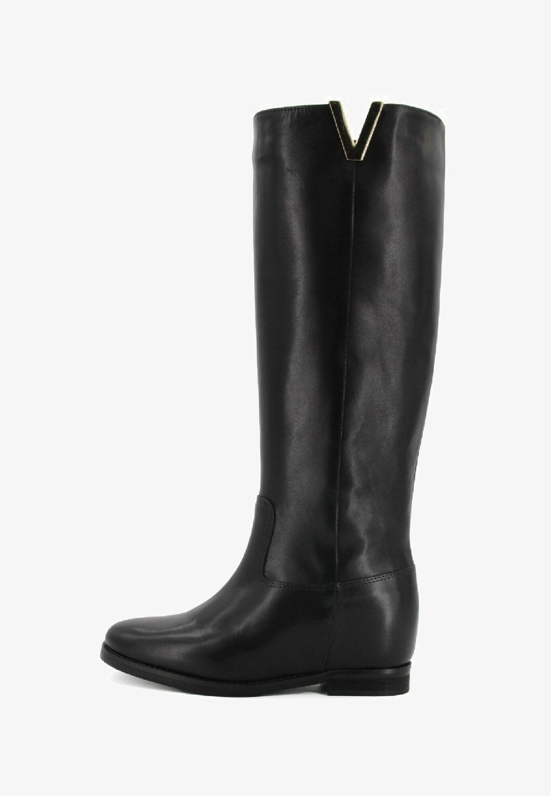 Stivale in pelle nera al ginocchio con tacco piatto, punta arrotondata e un accento metallico a forma di V nella parte superiore. Texture liscia e design semplice.