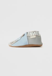 Zapato suave de cuero azul y gris con acentos de tela a rayas y suela antideslizante, que presenta una punta redondeada y una abertura elástica para facilitar su uso.